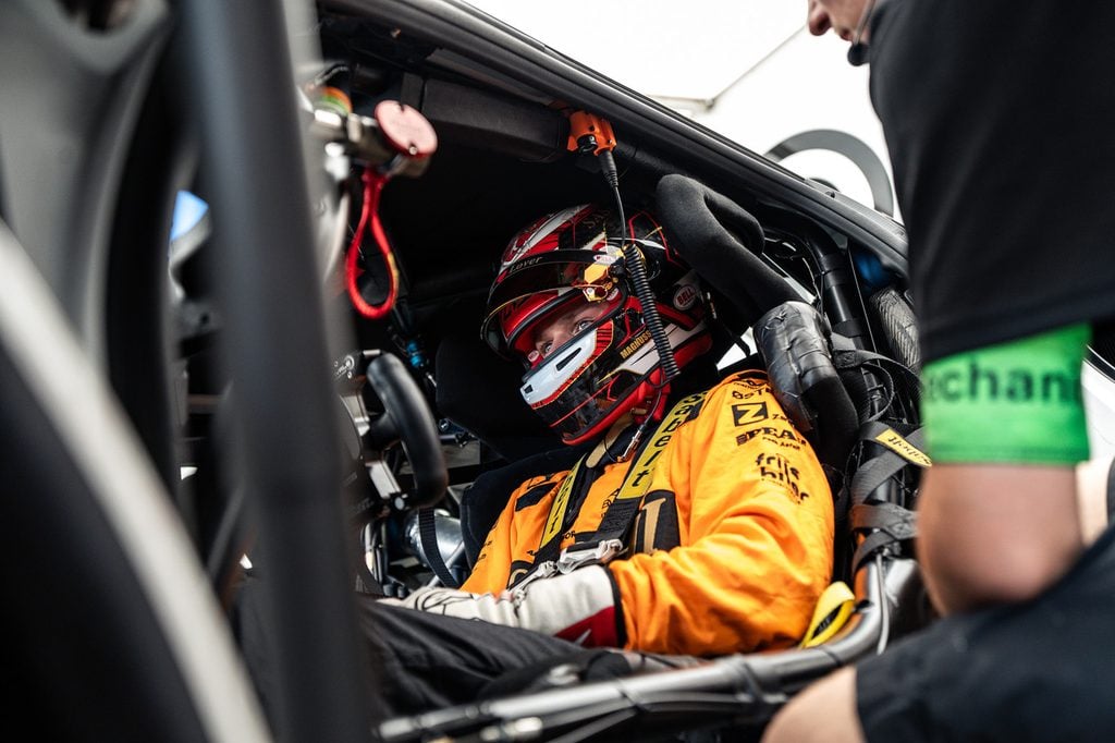 Luca misano 3 » admin by request Race car driver in an orange suit and helmet sits strapped in the cockpit, ready to race. » admin by request