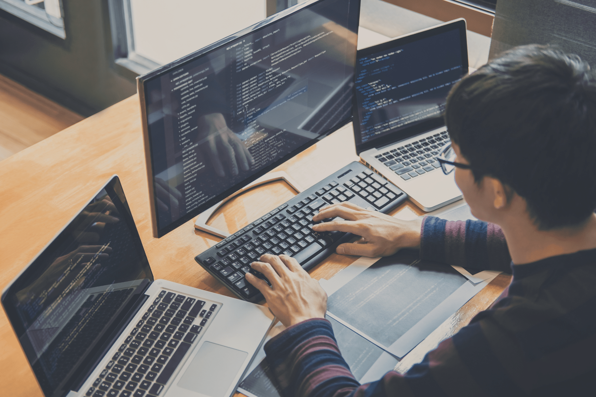 Discover our core features. A young male sits with his back to the camera typing on a keyboard, with three screens in front of him. » admin by request