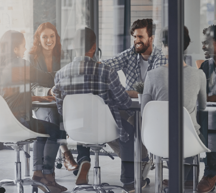 A photo through glass walls of six people in a meeting enjoying themselves. » admin by request