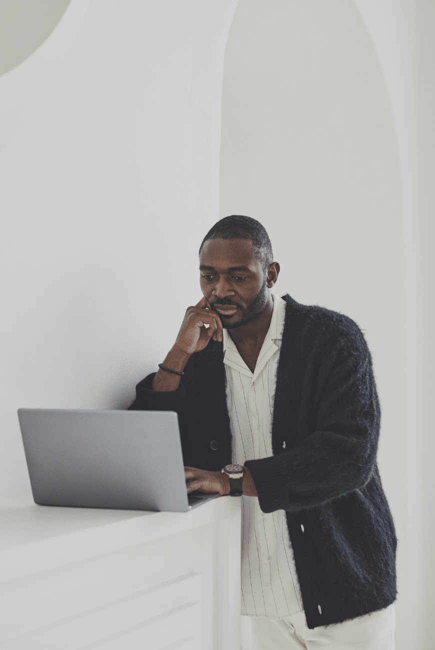 A standing man resting his head on his hand while using his laptop. » admin by request » admin by request