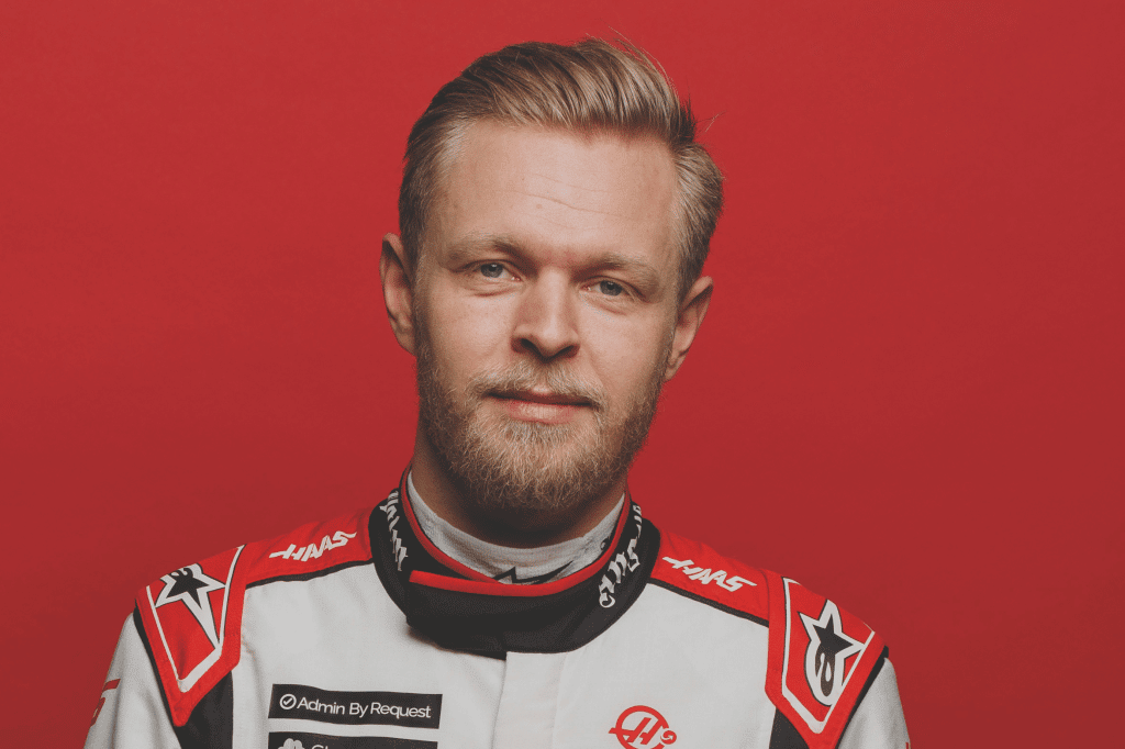 Partnership with Formula 1. Image of Kevin Magnussen from the chest up in his racing suit, on a red backdrop.
