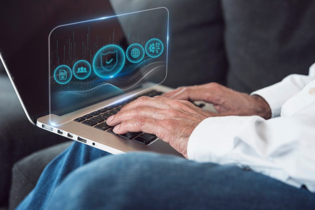 Top 10 pam 2024 5 » admin by request Close-up of hands typing on a laptop with holographic icons displaying security and analytics features.