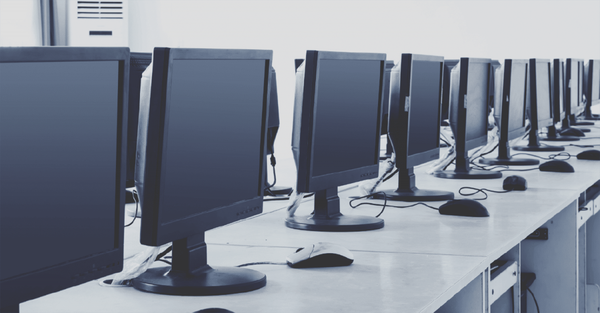 A long desk with a row of monitors on top of it.